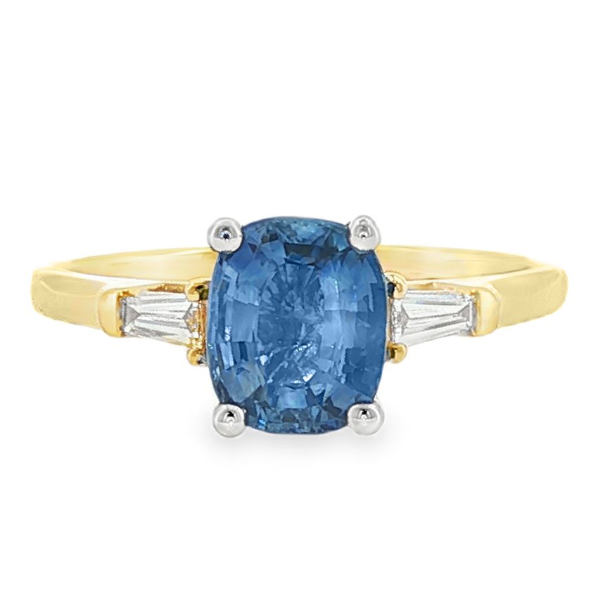 Oval light cornflower blue sapphire ring with tapered baguette diamonds in two tone 18k gold